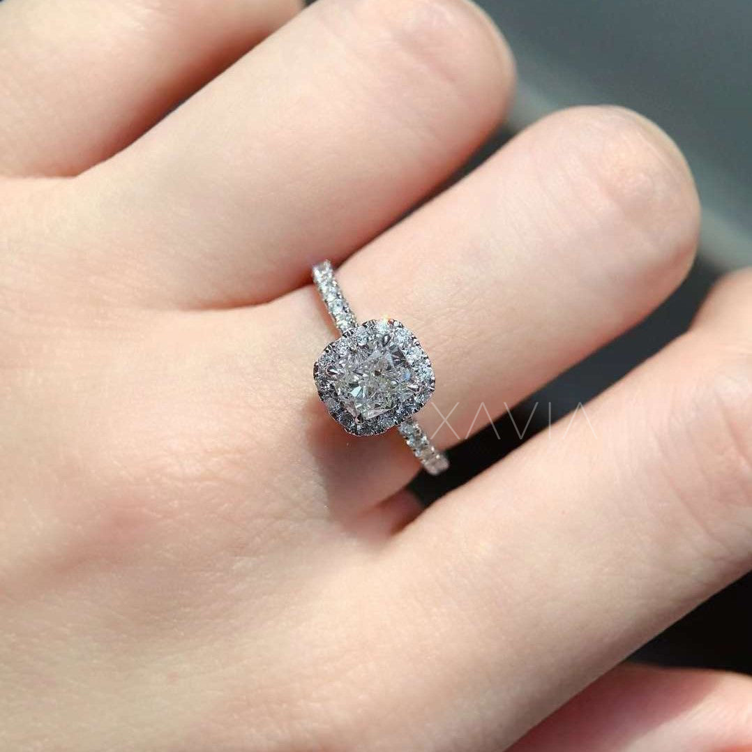 cushion cut diamond ring with halo and pavé band worn on hand